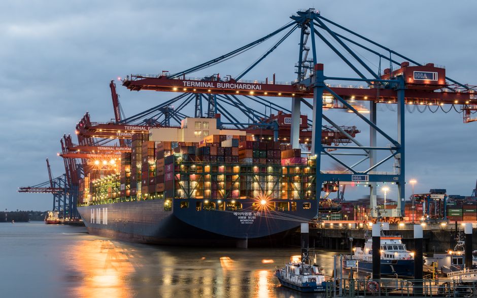 A cargo ship loaded with shipping containers at a port, representing import tariffs.