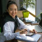 A self-taught student studying accounting concepts on a laptop at a bright desk