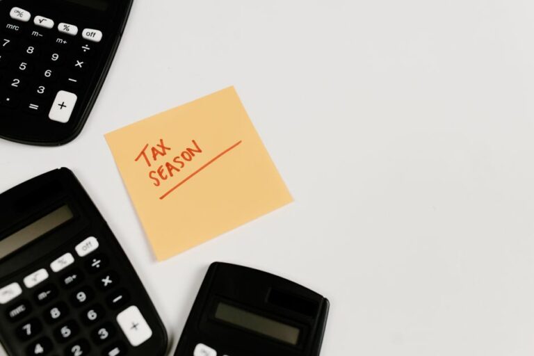 A calculator on tax forms next to a laptop