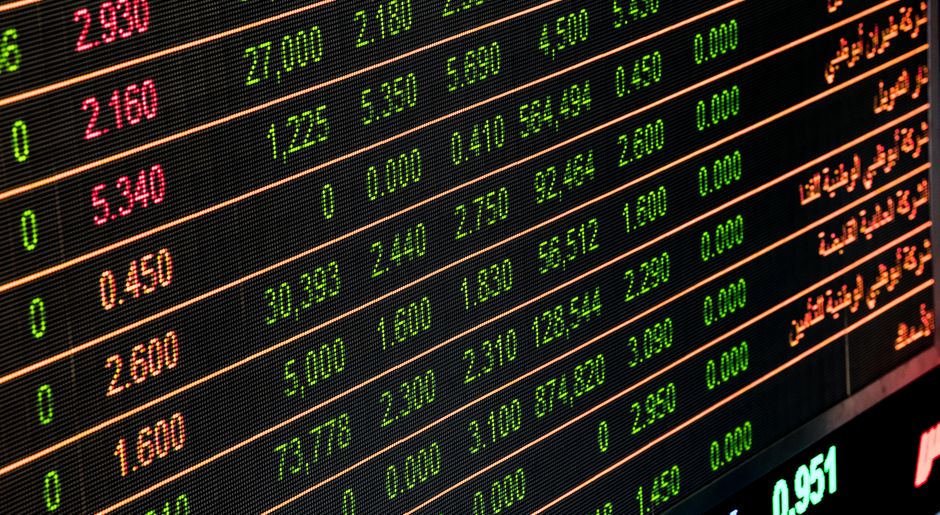 A professional desk displaying financial charts, stock market graphs on screens, and trading analysis data.