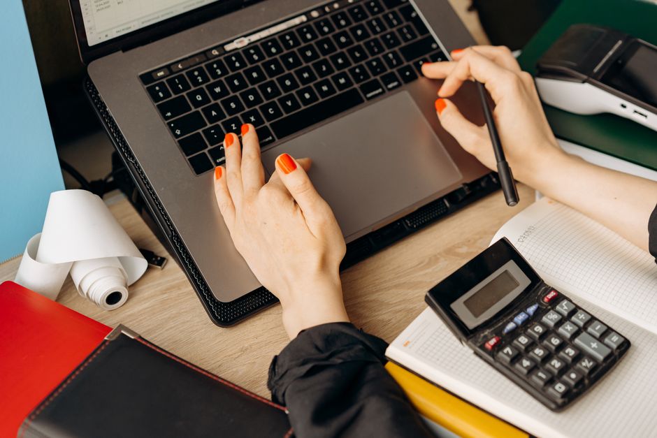An accountant posting adjusting journal entries for month-end accruals on an office keyboard.