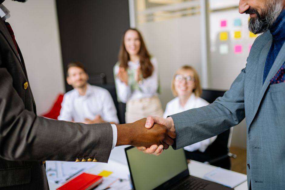 A business handshake in a bright office, symbolizing audit collaboration.