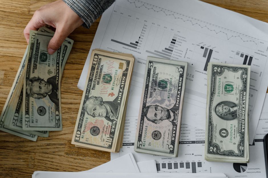 A stack of US dollar bills next to a bond yield curve chart showing flattening trends.