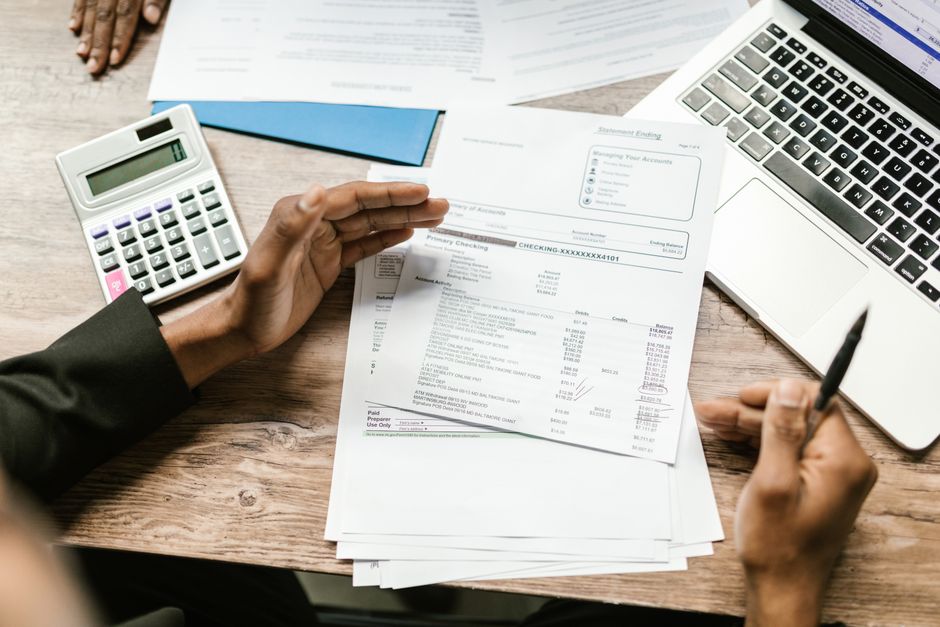 Bank statement documents and calculator on a desk for transaction verification.