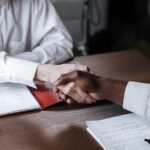 A job interview handshake in a modern corporate office.