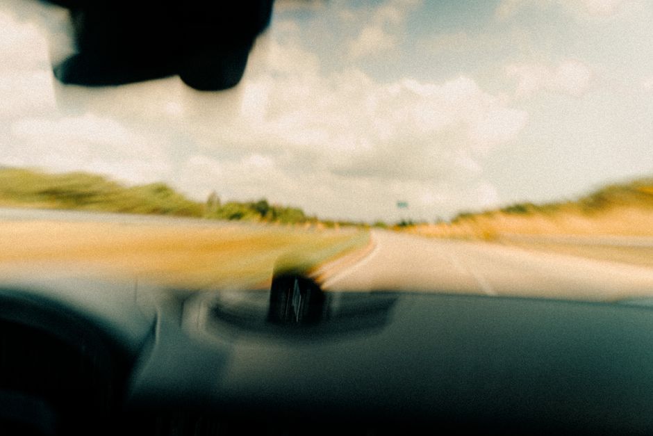 A car driving on a scenic highway representing business travel and standard mileage.