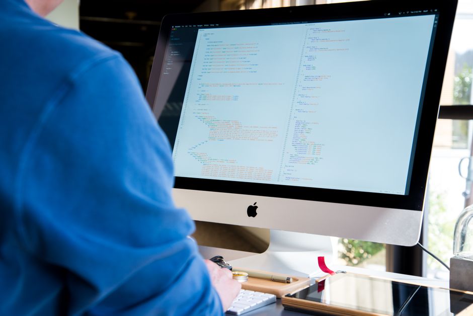 A software developer coding at a workstation with multiple monitors.