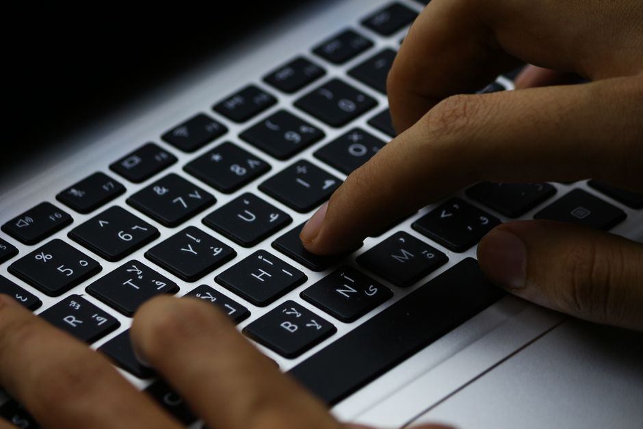 An accounting professional posting journal entries to an ERP system on a laptop.