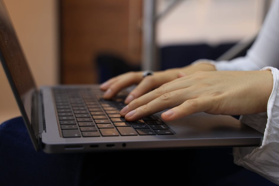Hands typing financial data onto a computer keyboard.